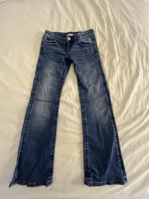 Blå low waist bootcut jeans Gina Tricot 146 - Säljer ett par blå bootcut jeans från Gina Tricot i storlek 146. Jeansen har snygga slitningar och broderade bakfickor med dekorativa detaljer. Klassisk femficksmodell och normal passform. Perfekta till en avslappnad look. En av knaparna saknas på rumpan! Priset kan diskuteras!🥰