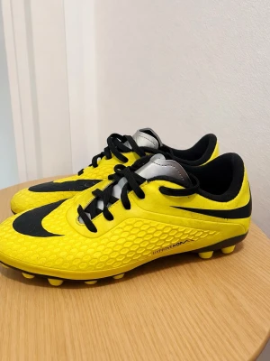 Nike Hypervenom gula fotbollsskor - Säljer ett par Nike Hypervenom fotbollsskor i gul och svart med cool struktur på ovandelen och svarta snören. Skorna har dobbar anpassade för konstgräs och en låg profil. Perfekta för dig som vill sticka ut på planen.