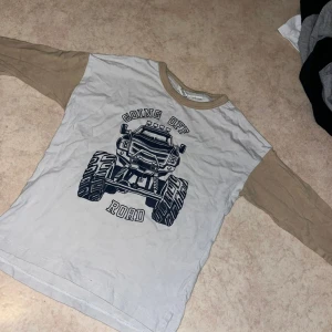 Vit långärmad tröja med offroad-tryck - Vit långärmad tröja med beige ärmar och coolt offroad monstertruck-tryck på bröstet. Rund hals med beige kant. Perfekt för dig som gillar bilar och streetstyle. Mjuk och skön.