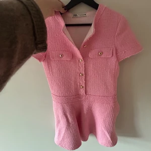 Rosa kortklänning från Zara - Supersöt rosa kortklänning från Zara med korta ärmar och guldknappar framtill. Använt cirka 2 gånger, inga defekter. 