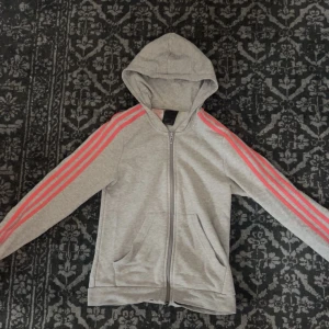 Adidas tjocktröja - En grå adidas kofta med rosa sträck på armarna.