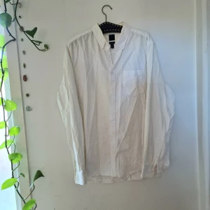 Vit skjorta från H&M i bomull - Vit skjorta från H&M i storlek L, tillverkad i 100% bomull. Skjortan har klassisk krage, lång ärm och knäppning framtill. Regular fit för en skön och avslappnad passform. Perfekt för dig som gillar enkel och clean stil.