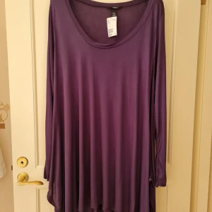 Lila långärmad tunika från H&M strl 3XL - Långärmad klänning i en snygg lila färg från H&M. Modellen har rund halsringning och är tillverkad i viskos. Storlek 3XL.