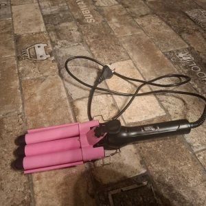 vågtång  - Trippeltång/vågtång för hårstyling i rosa och svart. Utrustad med två värmelägen (180°C och 210°C) och strömbrytare. Perfekt för att skapa stora vågor i håret snabbt och enkelt.