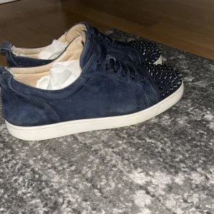 Mörkblå Christian Louboutin sneakers - Säljer ett par mörkblå loubs finte skick defekter hälen i skon lite risig men inget man ser när man har på sig dom och några av nitarna tappat lite färg st 44 skriv för mer info självklart äkta 