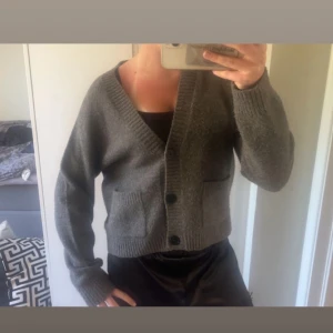 Grå stickad kofta med knappar - Mysig grå stickad kofta med två stora fickor framtill och djup v-ringning. Koftan har långa ärmar, ribbade muddar och helt perfekt till sena sommarkvällar.☺️💗