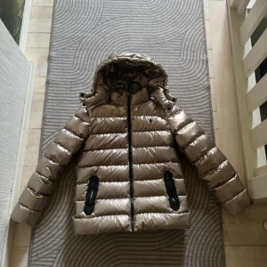 Ralph lauren jacka  - Snygg glansig beige pufferjacka från Polo Ralph Lauren med svart logga på bröstet.  Storlek xs knappt använd pris kan diskuteras 