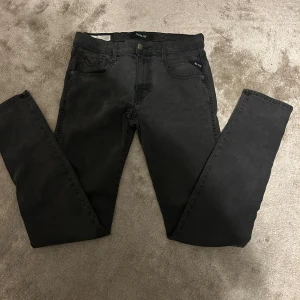 Svarta Replay jeans med smal passform - Snygga svarta jeans från Replay med klassisk femficksdesign och smal passform. Jeansen har svarta sömmar, knapp med Replay-logga och är tillverkade i ett mjukt bomullsmaterial med stretch för extra komfort. Har ni några frågor tveka inte för att höra av er 😁