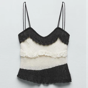Svartvit stickad tubtopp med volang - Supersöt stickad tubtopp i svart och vitt med volangdetaljer och vågig kant. Toppen har en bandeauform som sitter snyggt över bysten. Har klippt av banden så att den sitter som en bandeautopp och inte ett linne som på första bilden. Skriv vid fler frågor 