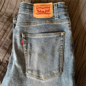 Levi's Loose Taper ljusblå jeans - Ljusblå jeans från Levi's med loose taper passform. Klassisk Levi's röda etikett på bakfickan och läderpatch i midjan. Jeansen har avsmalnande ben och är tillverkade i slitstarkt denimtyg. Perfekta för en avslappnad och trendig look. Bra skicka inga defekter. Storlek 16a 170/176