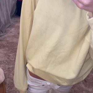 Ljusgul sweatshirt i bomull - Enkel och stilren ljusgul sweatshirt med rund hals och ribbade muddar. Tröjan har en loose passform och är tillverkad i mjuk bomull, perfekt för en chill och avslappnad look. Passar bra till jeans eller mjukisbyxor.