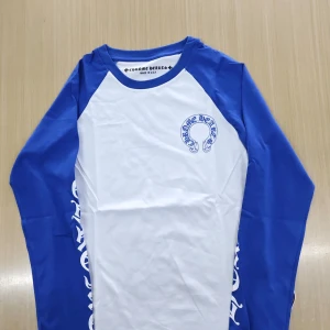  CH tröja  - Säljer en blåvit långärmad tröja från Chrome Hearts med stora tryck på ryggen och ärmarna. Tröjan har raglanärmar i blått och kroppen i vitt, med coola loggor och text i blått. Tillverkad i mjuk bomull, perfekt för dig som gillar streetwear vibes. Den är s men passar M också 