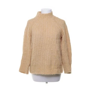 Gul stickad tröja med hög krage - Mysig gul stickad tröja med hög krage och långärmad modell. Tröjan har en chunky struktur och är perfekt för kyliga dagar. Den har en avslappnad passform och ribbade detaljer vid ärmslut och nederkant.