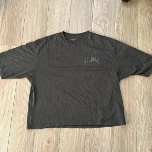 Svart oversized t-shirt från YoungLA i storlek L - Svart t-shirt från YoungLA med stort tryck på ryggen och mindre logga på bröstet. Oversized passform och klassisk rund hals. Tillverkad i mjuk bomull, perfekt för en avslappnad streetwear-look.