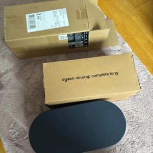Dyson Airwrap Complete Long HS05 - Dyson Airwrap Complete Long HS05 i färgen dark blue/copper. Kommer i originalförpackning med flera tillbehör och elegant förvaringsväska. Produkten ser ut att vara i mycket gott skick, utan synliga defekter eller slitage. Perfekt för styling och torkning av håret.