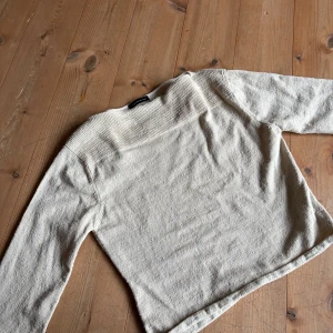 Beige stickad tröja från Lene Sand - Säljer en beige stickad tröja från Lene Sand med lång ärm och ribbad detalj upptill. Tröjan har en rak passform och är tillverkad i ett mjukt material som känns skönt mot huden. Perfekt för lager-på-lager under kyliga dagar.