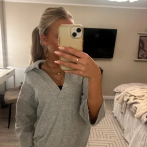 Grå stickad kofta med krage - Snygg grå stickad kofta med bred krage och v-ringad hals. Modellen är loose fit med långa ärmar och ribbade muddar. Perfekt att slänga på sig för en chill look. Mjuk och skön känsla, passar till jeans eller leggings.