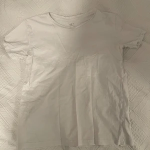 Vit basic t-shirt från 157 - Enkel vit t-shirt från 157 med rund halsringning och korta ärmar. Perfekt som basplagg och lätt att matcha med allt. 