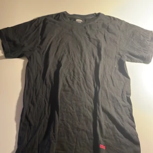 Svart Supreme t-shirt i bomull - Svart t-shirt från Supreme med klassisk röd box logo tryckt längst ner på framsidan. Skön passform och tillverkad i mjuk bomull. Perfekt för dig som gillar streetwear och vill ha en clean look med ikonisk Supreme-vibe. Nypris på denna är ca 2000-3000kr men jag lägger ut den för 450kr