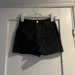 Svarta högmidjade shorts XS - Snygga svarta högmidjade shorts från shein i en glansig finish som ger en cool look. Klassisk femficksmodell med knapp och dragkedja framtill. Storlek XS, stretchigt 