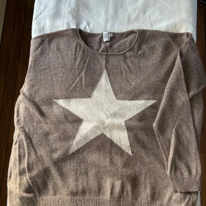 Beige stickad tröja med stjärna från Saint Tropez - Beige stickad tunn tröja från Saint Tropez i storlek S. Tröjan har en stor stjärna framtill, rund halsringning och långa ärmar. Materialet är en mjuk mix av viskos, polyamid och ull. 