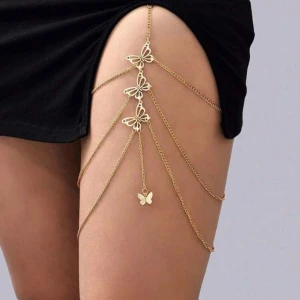 Guldigt lårbenshalsen med fjärilar - Unikt lårhalsband i guldtonad metall med flera kedjor och detaljerade fjärilar. Kedjorna sitter ihop med en elastisk svart rem för perfekt passform. Perfekt accessoar för att sticka ut och ge outfiten en extra touch.