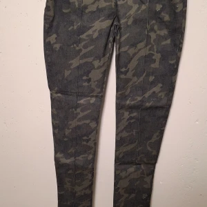 Camo skinny jeans i mörkgrå denim - Snygga jeans med camouflage-mönster i mörkgrå och svarta toner. Modellen är skinny med smal passform och klassisk femficksdesign. Materialet är jeans och byxorna har en modern streetkänsla som passar perfekt till sneakers.