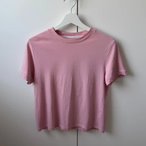 Ljusrosa t-shirt från SOC i bomull - Enkel och stilren ljusrosa t-shirt från SOC i mjuk bomull. Klassisk rund halsringning och korta ärmar. Perfekt för en chill och avslappnad look. Passar dig som gillar basic och bekväma plagg.