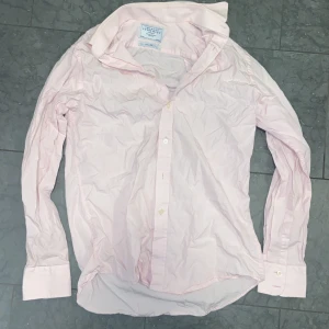 Ljusrosa skjorta Charles Tyrwhitt - Säljer en ljusrosa skjorta från Charles Tyrwhitt i slim fit-modell. Skjortan har klassisk krage, långa ärmar med manschett och knappar framtill. Tillverkad i mjuk bomull och passar perfekt för en clean och stilren look.