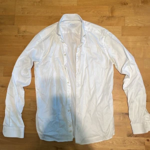 Vit skjorta Super Slim från Eton - Klassisk vit skjorta från Eton i modellen Super Slim. Skjortan har lång ärm, knappar framtill och en snygg, stilren krage. Perfekt för dig som gillar en tajtare passform och vill ha en clean look. Tillverkad i bomull för en skön känsla. (Storlek M)