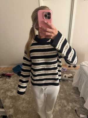 Randig stickad tröja i svart och vitt - Säljer en snygg stickad tröja med breda svarta och vita ränder. Tröjan har ett hålmönster i ränderna och är långärmad med rund hals. Perfekt för dig som gillar en chill och trendig stil.