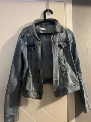 Klassisk ljusblå jeansjacka - Snygg ljusblå jeansjacka med klassisk krage och bröstfickor. Knapparna har rostat 