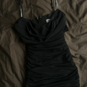 Oh Polly Klänning - Svart klänning från Oh Polly med glittriga axelband och draperad front och öppning. St 8/S men skulle säga XS! Aldrig använd, nypris ca 700 kr