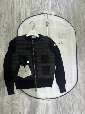 Moncler cardigan dam  - Hej! En Moncler cardigan för dam till salu. Jackan är i jättefint skick och har inga defekter eller liknande. Den är äkta och köpt online  kvittot finns. Jag säljer den pågrund av att den inte riktigt passar min stil. Den är jättefin och jag fick alltid jätte många komplimanger när jag andvände den. Moncler dustbag lapprna osv ingår med jackan. Hör av dig vid minsta lilla fråga! 💕