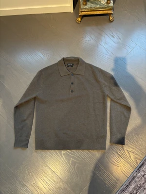 Brun polotröja från Massimo Dutti - Snygg brun polotröja från Massimo Dutti i 100% ull. Tröjan har klassisk krage, tre knappar framtill och ribbade muddar vid ärmslut och nederkant. Perfekt för dig som gillar stilrena och tidlösa plagg med en chill vibe. Använd 1 gång. Nypris 1000 kr