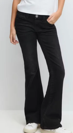 Svarta bootcut jeans - Snygga svarta jeans med bootcut passform och klassisk femficksdesign. Jeansen har normal midja och är tillverkade i ett mjukt denimtyg som sitter skönt hela dagen. Perfekta för dig som gillar en retro vibe och vill ha ett par jeans med lite extra sväng i benen.