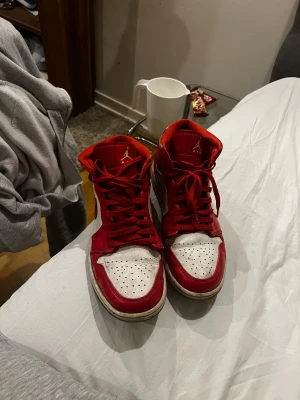 Nike Air Jordan 1 Retro röd/vit - Nike Air Jordan 1 Retro sneakers i rött och vitt med klassisk Jordan-logga på sidan och tungan. Skorna har snörning, rund tå och färgglada detaljer runt ankeln. Ovandelen är i skinn och textil, med en platt sula och ikonisk Swoosh på sidan. Går även att lösa en skyst deal vid en snabb affär. MVH Gabriel 