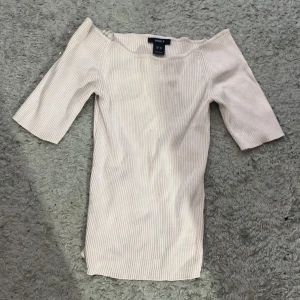 Ljus rosa ribbad offshoulder topp - Säljer en ljus rosa ribbad topp från Lindex med offshoulder-design och halvlånga ärmar. Toppen har en slim passform (Den anpassar sig för din kroppsform) och är tillverkad i mjuk bomull som känns skön mot huden. Perfekt för dig som gillar stilrena och enkla plagg men lite varmare.