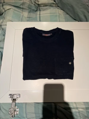 Navy blå t-shirt från Morris XS - Svart t-shirt från Morris i storlek XS. Klassisk rund hals och en liten bröstficka med Morris broderad logga. T-shirten är gjord i mjuk bomull och har en clean, stilren look som funkar till allt. Perfekt basic-plagg med snygg passform.