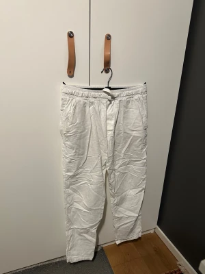 Vita linnebyxor  - Säljer ett par vita linnebyxor med elastisk midja och snörning framtill. Byxorna har sidofickor och två bakfickor, samt en avslappnad passform. Perfekta för chill dagar och har en lätt, luftig känsla tack vare linnematerialet. Från Zara.