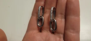  Helt nya silver 925 örhängen med glittriga stenar - Helt nya silver 925 örhängen med rektangulär form och glittriga stenar längs ena delen. De har en cool länkdesign med två sammankopplade delar, varav en är slät och den andra är dekorerad med små stenar. Perfekt för dig som gillar stilrena detaljer med lite extra bling.