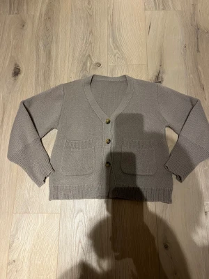 Ljus brun stickad kofta med knappar strl S -  Ljusbrun stickad kofta i strl S med v-ringad hals och tre snygga knappar framtill. Koftan har två praktiska fickor och ribbade muddar vid ärmslut och nederkant. Perfekt för lager-på-lager och chill dagar. Skulle även säga att den passar Xs 💗