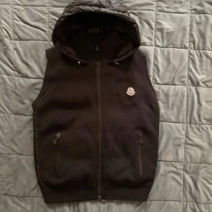 Moncler Tricot väst - Säljer nu min tvärfeta Moncler Tricot väst. Västen är i använt men fint skick! Inga defekter endast kanske lite nopprig någonstans vilket går att ta bort. Västen är mörkbrun men kan se svart ut beroende på ljuset. Hör av er vid funderingar! 😊Storlek L (passar M)