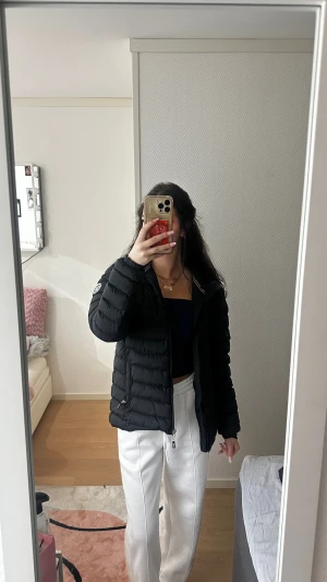 Svart pufferjacka Vinson Polo Club L - Svart pufferjacka från Vinson Polo Club i storlek L. Jackan har huva, dragkedja framtill och ett broderat märke på ärmen. Snygg quiltad design och sportig look, perfekt för kyliga dagar.