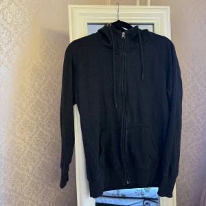 Svart hoodie med dragkedja och huva - Svart hoodie med hel dragkedja framtill, huva med snörning och två rymliga fickor. Mjuk insida och ribbade muddar vid ärmar och nederkant. Är ett set, kolla in min profil och du vill köpa byxorna.