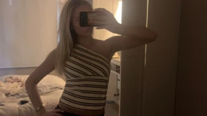 Randig one shoulder topp i bomull - Säljer en vit och svart randig one shoulder topp med diagonala ränder. Toppen är ärmlös och har en tight passform som sitter snyggt mot kroppen. Tillverkad i mjuk bomull, perfekt för varma dagar. Snygg och trendig design som sticker ut.