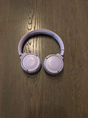 JBL trådlösa over-ear hörlurar - Snygga lila JBL trådlösa over-ear hörlurar i fint skick. Mjuka öronkuddar och justerbar bygel för bekväm användning. Inga synliga defekter eller slitage. Perfekt för musik, samtal och gaming med bra ljudkvalitet.