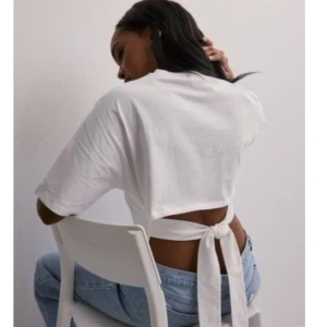 Vit croppad topp med knyt - Säljer en vit croppad topp med korta ärmar och snygg knytning i ryggen. Toppen har öppen rygg och är tillverkad i mjuk bomull, perfekt för dig som gillar trendiga detaljer. Ny pris 249kr