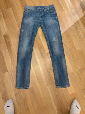 Blå  jeans från George, stl 31 - Snygga blå jeans från George i skinny fit-modell. Jeansen har klassisk femficksdesign, orangea sömmar på bakfickorna och lätt slitna detaljer för en cool look. Tillverkade i mjukt denimtyg som sitter tajt längs benen.