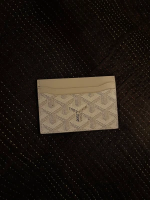 Korthållare - Vit korthållare i stilren design  Snygg och praktisk korthållare i vitt med klassiskt mönster. Har flera fack för kort och fungerar perfekt i både små väskor och fickor. Använd få gånger och i fint skick.  Perfekt för dig som vill ha en liten och smidig korthållare till vardags!